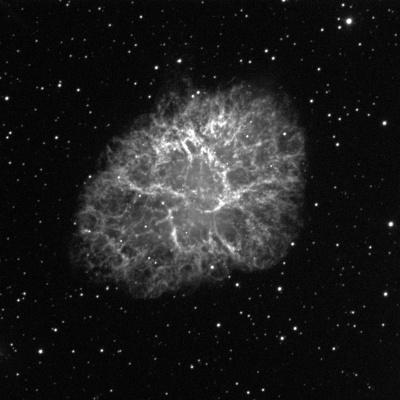 A cloud in the shape of an elongated, stretched oval (pointing towards upper right and lower left corners) sits in the middle of the image against a black background with small dots of white stars. The cloud is various shades of grey and white.