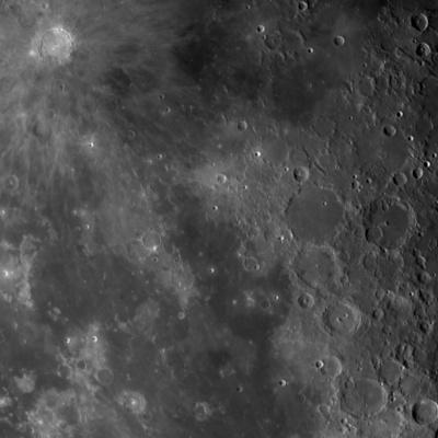 A zoomed in section of the Moon. The surface is shades of light and dark grey with many craters that range in size.