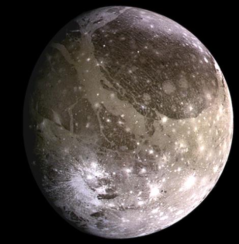 Image of Ganymede, Jupiter's largest moon, showing a surface marked with bright and dark regions, craters, and long, light-colored grooves and ridges