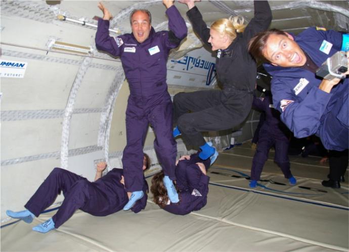 A picture showing people appearing to float in the air inside of a NASA plane.